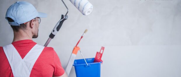 A man painting a wall with paintig equipment